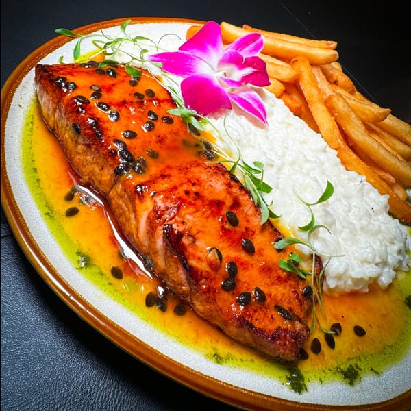 Grilled salmon with passion fruit sauce, white rice, french fries, and a pink orchid.