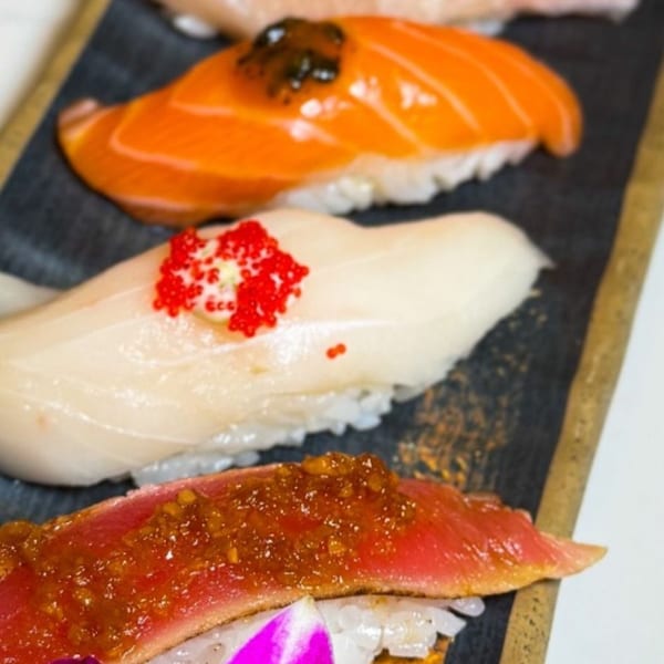 Close-up of four pieces of Temak House nigiri sushi with various fish toppings and garnishes.
